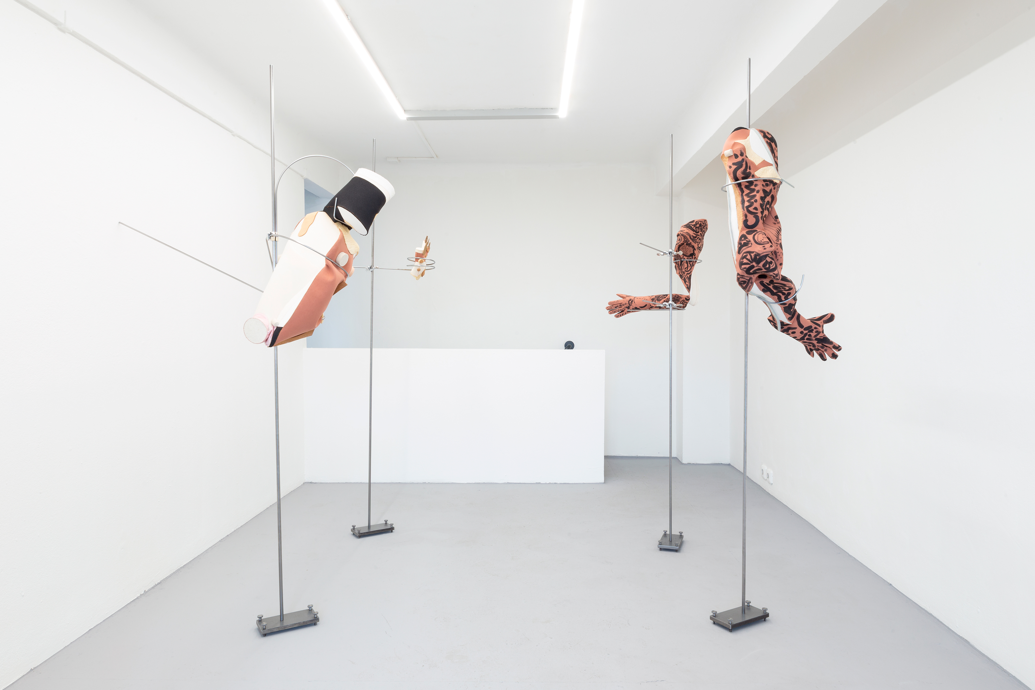 Photo of an art installation called Hands (and Other Products of Labor) by Klára Čermáková (Diploma Projects 2020, UMPRUM — Academy of Arts, Architecture & Design in Prague, Czechia) [view on first half]. Four sculptures (different parts of the human body), each hanging on a subtle metal construction.