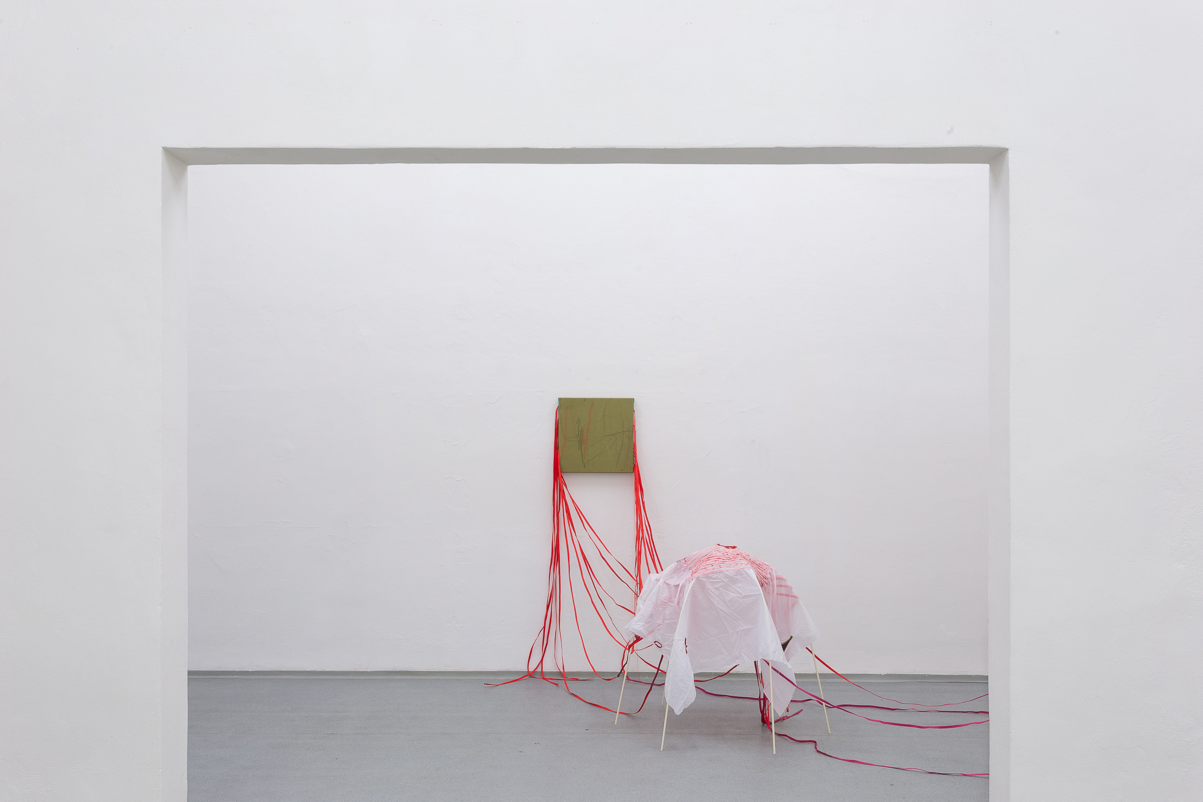 Photo of an art installation called Hands (and Other Products of Labor) 2.0 by Klára Čermáková (Mikulov Art Symposium, Mikulov, Czechia, 2021) [View on the back room 1]. A view into the back room shows a smaller metal skeleton covered in fabric loosely connecting to the stitched paintings hanging on the walls.