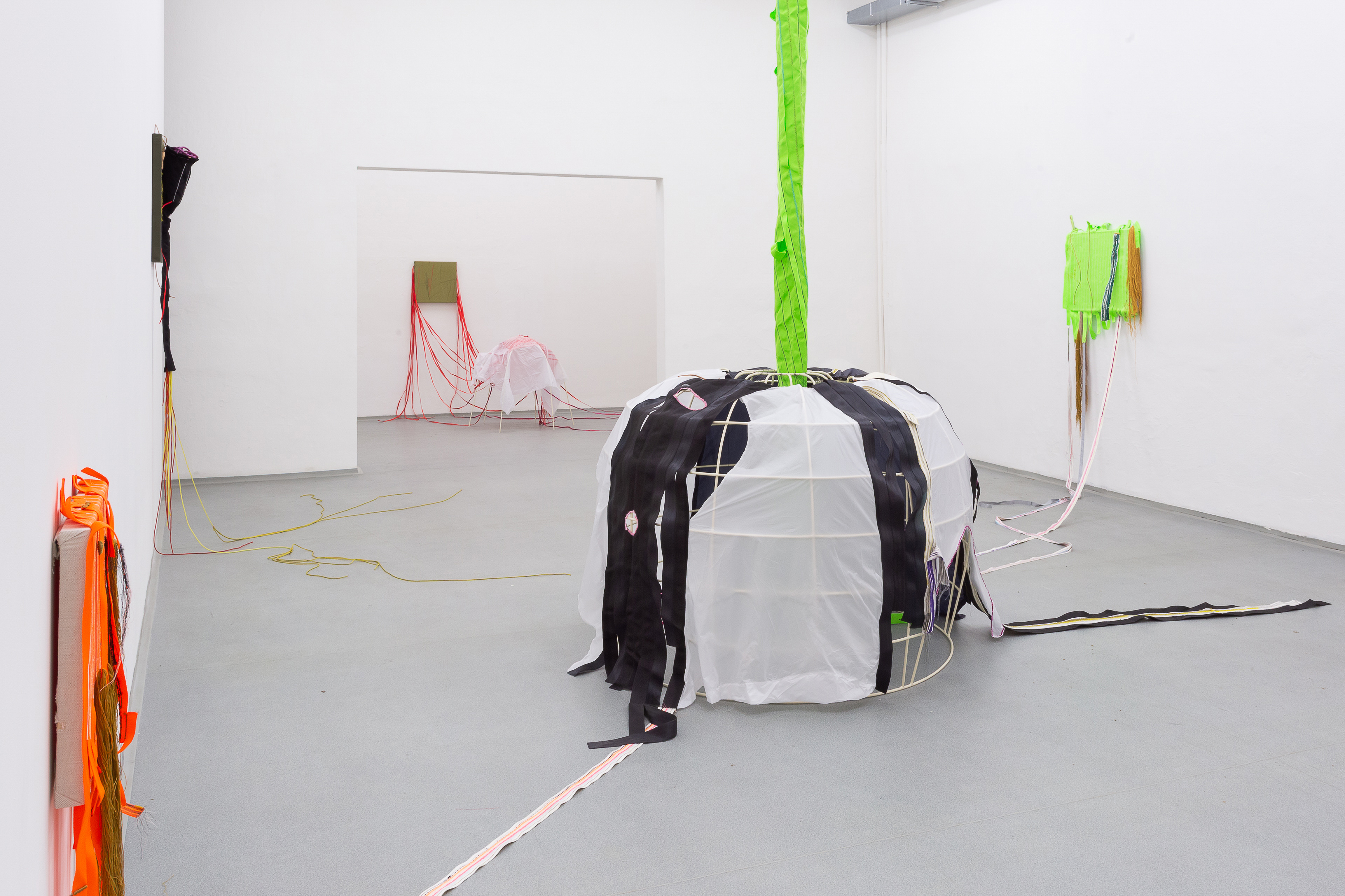 Photo of an art installation called Living Tent by Klára Čermáková (Galerie FaVu, Brno, Czechia, 2018) [Front view]. Front view of the central object of the exhibition (the tent) and the stitched paintings hanging on the walls connected to it.